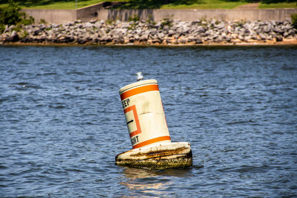 floating bouy in lake saying Keep Right bobbing on rough water with relfection and blurred shore and rip rap in distance