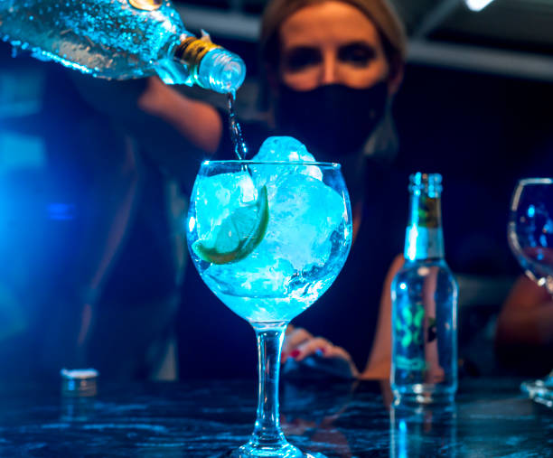 Young waitress with protective mask prepares a gin and tonic cocktail in a nightclub. stock photo