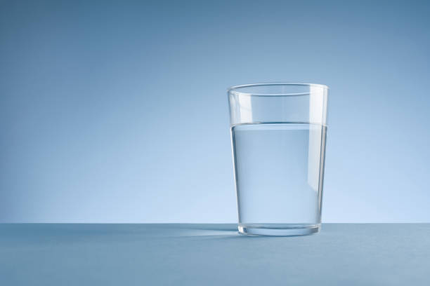 Cтоковое фото Минималистичное фото стакана чистой питьевой воды на синем фоне