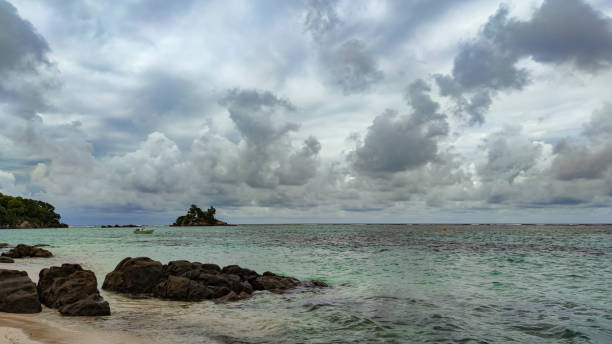 istock Cloudly sky on Anse Royale beach, Seychelles, small boat and island 1330409930