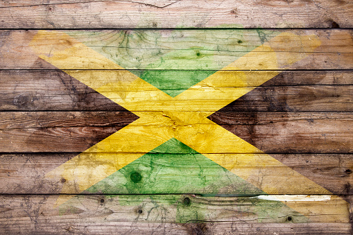 Flag of Jamaica watercolor painted on a old wooden boards. Grunge flags texture. Background concept. Full color. Horizontal orientation. Faded effect.