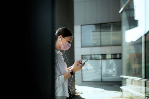 istock Businesswoman using a smartphone on the street while wearing a facemask 1330410759