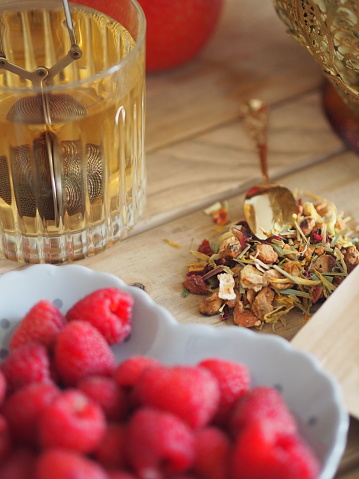 Ice tea with raspeberries. Dried tea leaves and gold spoon.