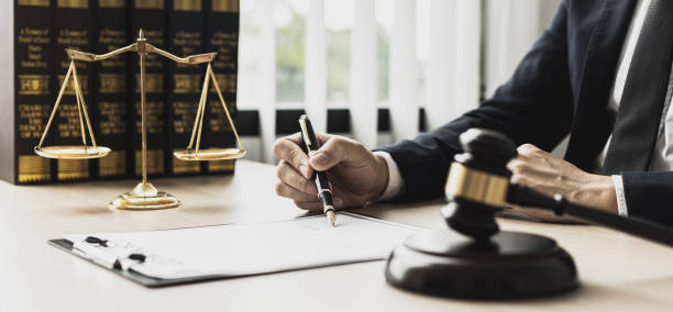 A male lawyer is signing a plea agreement with a client in a fraud case, in which the client has filed a lawsuit against an employee at a company that commits the fraud. Fraud litigation concept. A male lawyer is signing a plea agreement with a client in a fraud case, in which the client has filed a lawsuit against an employee at a company that commits the fraud. Fraud litigation concept. notary stock pictures, royalty-free photos & images