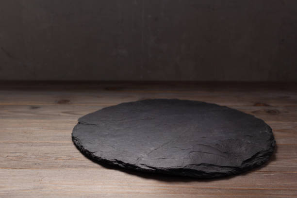 istock Slate pizza cutting board for homemade bread cooking or baking on table. Empty pizza board at wooden tabletop background 1330416976