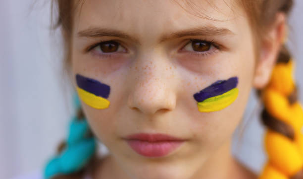 close-up girl's face with yellow-blue national flags of ukraine painted on her cheeks. - 烏克蘭文化 圖片 個照片及圖片檔