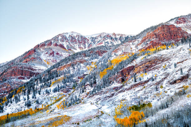 Photo of Maroon Bells red mountains peak in Aspen, Colorado covered in snow after winter storm froze in autumn fall October change of seasons