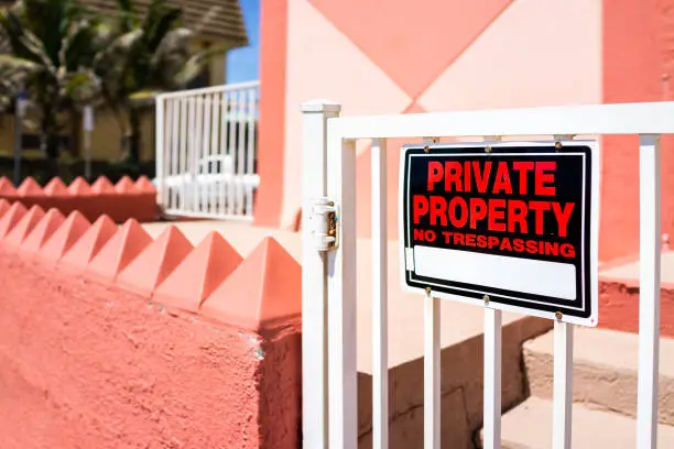 Private property no trespassing sign hanging on door fence outdoors on street by house home building entrance in Hollywood beach broadwalk in Miami, Florida