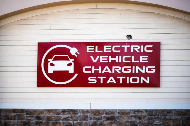 Sign on street road for Electric Vehicle Charging station with logo on building in Riverton Commons Plaza in Front Royal, Virginia USA