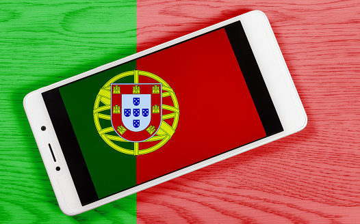 Bandera portuguesa creativa que consiste en un teléfono inteligente sobre un fondo de madera photo