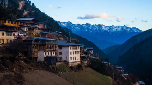 An iconic view of Yubeng village in Yunnan, China. Yubeng village is a Tibetan village at the foot of the Meili Snow Mountain range, at an altitude of over 3000m above sea level. A group of youth hikers can be seen here, descending down towards the village.