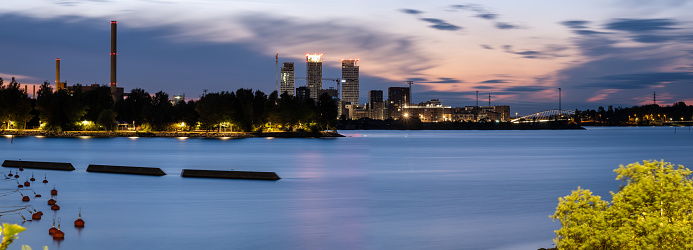 Helsinki / Finland - JULY 20, 2021: A colorful night cityscape of a modern residential district. Highrise buildings in the background.