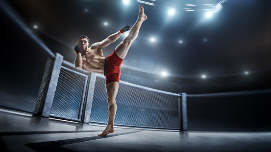 Martial arts fighter (MMA) jumping with a knee kick. Smoke background