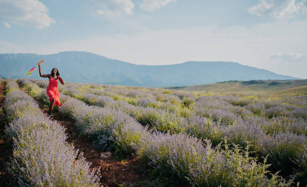 Woman running with a kite on a meadow at sunset