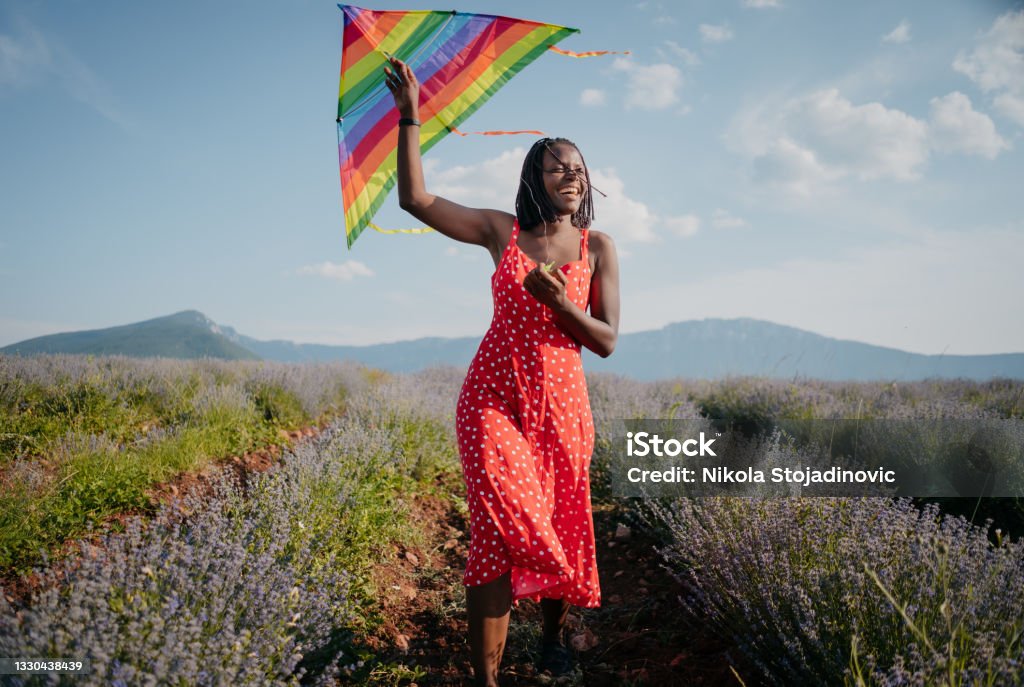 Woman running with a kite on a meadow at sunset Kite - Toy Stock Photo