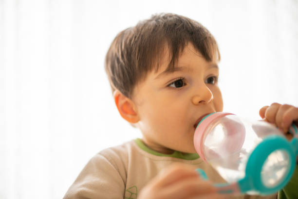 istock Little boy drinking water from a bottle. 1330445652