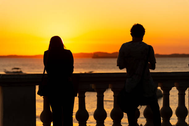 Salvador, Bahia, Brazil - May 21, 2021: Silhouette of people enjoying the sunset on Porto da Barra beach. A moment of relief from the stress of the pandemic.