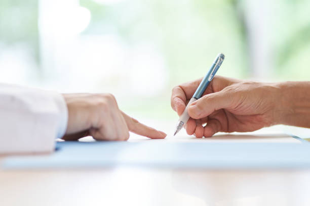 personnes âgées signant avec un médecin expliquant le contrat - engagement photos et images de collection