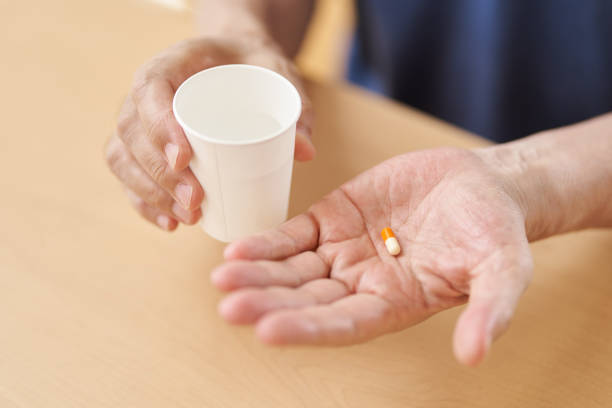 mains des personnes âgées qui boivent des médicaments - médicament générique photos et images de collection