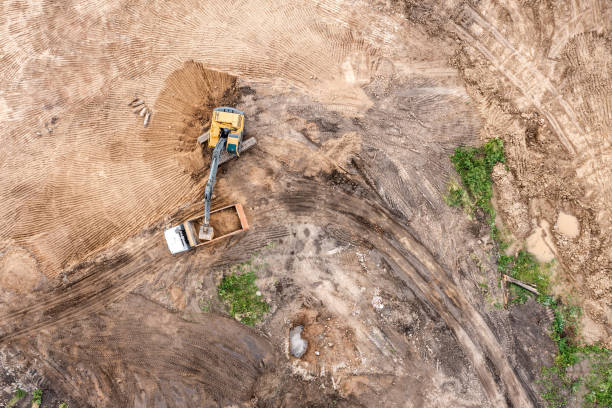 istock excavator is loading soil into a dump truck. earthworks on construction site. working industrial machines. aerial view from above. 1330480838