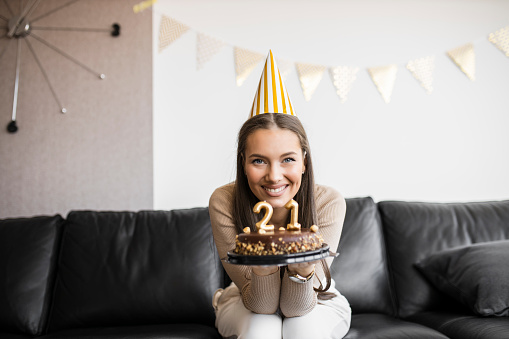 Young beautiful woman celebrating her 21's birthday with chocolate cake at home
