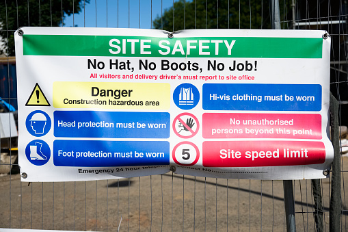 Construction site health and safety message rules sign board signage on fence boundary uk