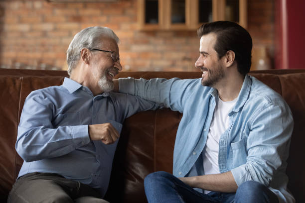 istock Happy grown son and older father resting on couch 1330499321