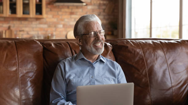 istock Happy mature senior 70s man using laptop, sitting on sofa 1330499322