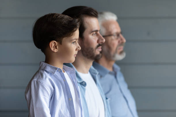 Serious thoughtful boy kid standing in row with young fath Serious thoughtful cute boy kid standing in row with young father and senior grandfather, looking forward, thinking of future. Intergenerational family portrait with three male generations critical thinking kids stock pictures, royalty-free photos & images