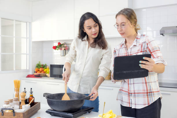 While cooking meals in the kitchen, a happy couple uses a smart tablet to look up a recipe online.