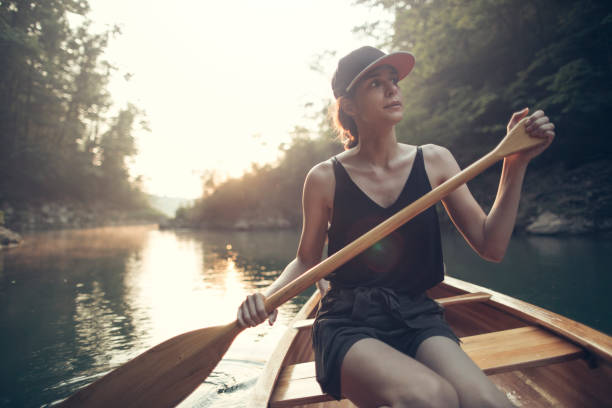 Woman rowing a rowboat and having fun in nature. Boating in summer. Smiling happy lady enjoying outdoor activity. Girl on row boat in Central Park, New York. Wanderlust, freedom and healthy lifestyle.