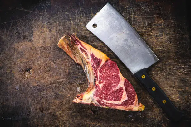 Butcher meat cleaver and dry-aged beef veal steak fillet of thick meat, on butcher chopping table