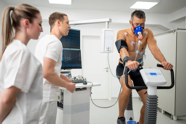 Man taking a cardiopulmonary stress test in clinic Mature man taking a cardiopulmonary exercise test by riding a cycle ergometer in clinic stress test stock pictures, royalty-free photos & images