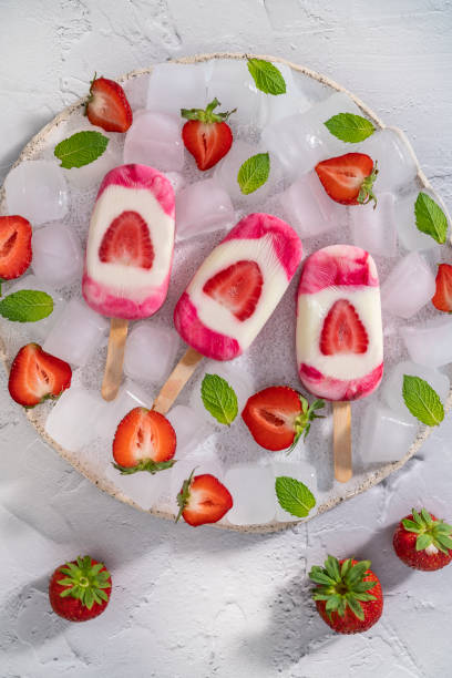 istock Strawberry handmade popsicles with mint leaves on ice cubes in white plate on white background 1330510234