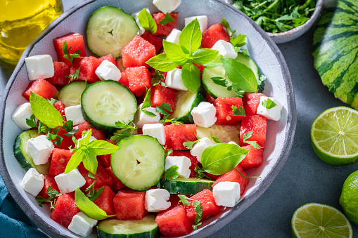 Healthy vegetarian watermelon salad bowl with feta cheese, cucumber and parsley on gray background macro closeup, Mediterranean diet