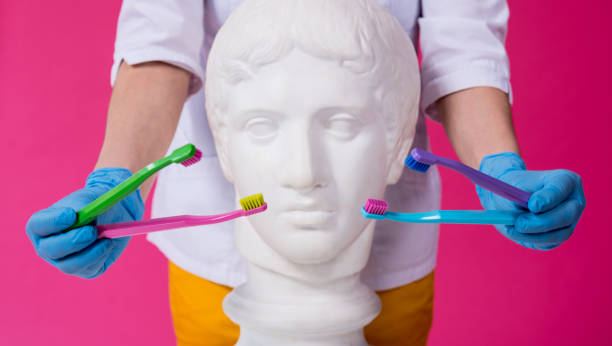 istock Woman dentist brushing teeth of an antique statue using a four toothbrushes 1330510662