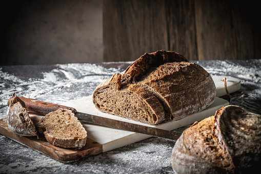 Sourdough bread brown cut slices wholegrain homemade German style on cutting board with slices on white flour background