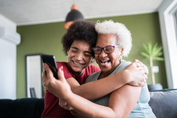 nonna e nipote si abbracciano mentre fanno una videochiamata a casa - grandparent family multi generation family technology foto e immagini stock
