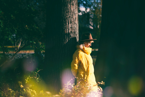 Cute young woman in a yellow jacket and hat melancholy walking in autumn park