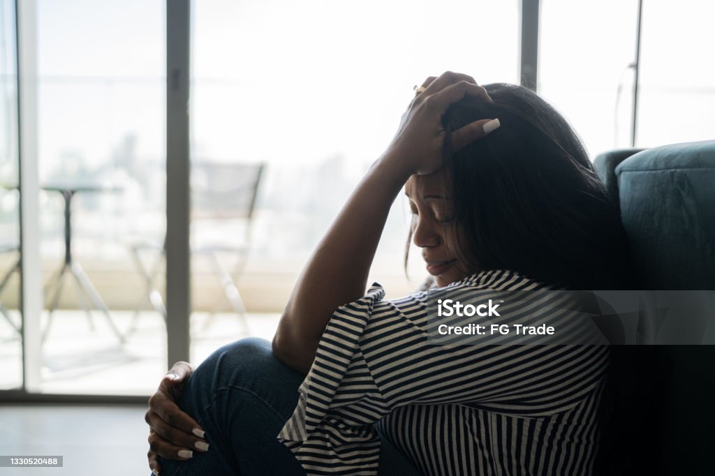 Depressed mature woman sitting on the ground at home Shock Stock Photo