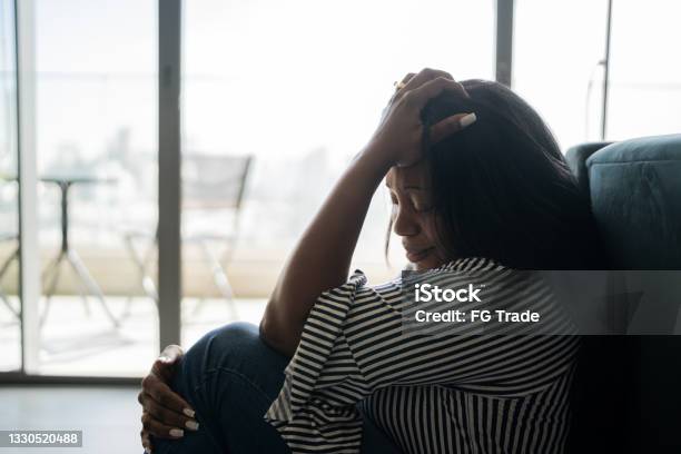 Depressed Mature Woman Sitting On The Ground At Home Stock Photo - Download Image Now