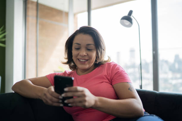 istock Mature woman sitting on the couch using smartphone at home 1330522042