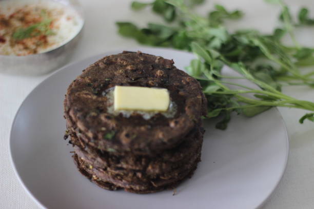 Flatbread with finger millet and fenugreek leaves served with masala curd. It is also called Nachni methi thepla, a healthy and tasty flat bread from Gujarat, India