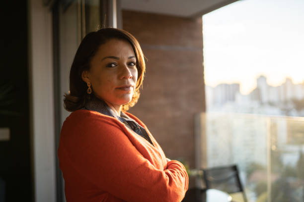 Portrait of a mature woman by the window at home Portrait of a mature woman by the window at home serious stock pictures, royalty-free photos & images