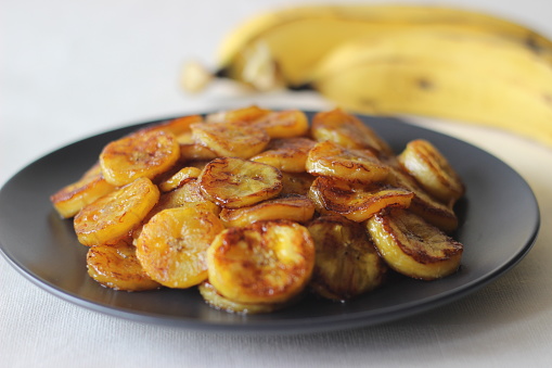 Caramelised plantain slices. A traditional tea time snack from Kerala.Cut ripe plantain into slices and toast it in a pan adding ghee n some brown sugar. Shot on white background.