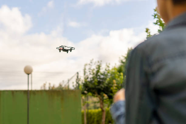istock Boy on his back flying his toy drone in a public park 1330528125