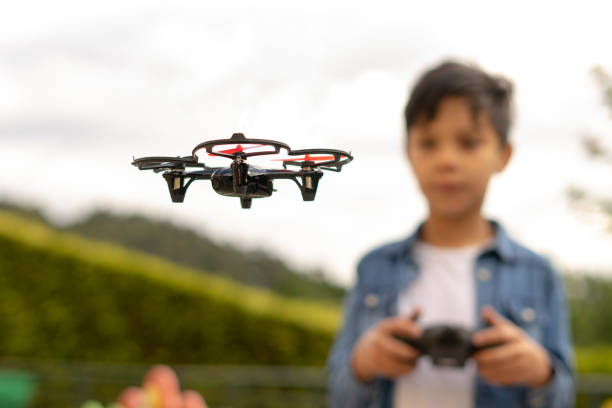 Concentrated boy flying his toy drone with remote control in his hands in a park. Selective focus stock photo