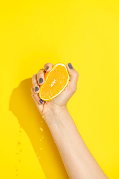 sujete de la mano, exprimiendo la naranja a la mitad - freshly squeezed fotografías e imágenes de stock