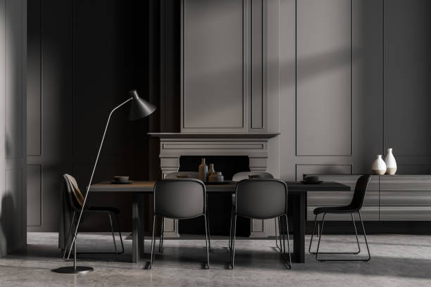 istock Minimalistic grey dining room interior with long table, black chairs and fireplace 1330538068