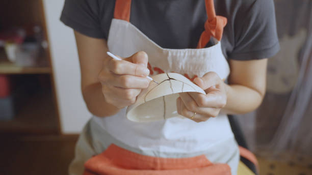 istock Woman repairing broken pottery. Kintsugi. 1330540397